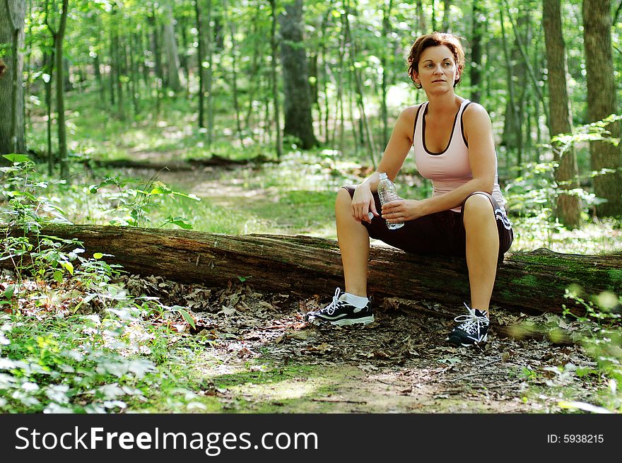 Mature woman runner resting in woods.