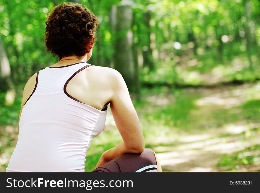 Mature woman runner resting in woods.