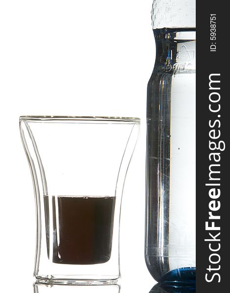 A waterbottle and a glass with a dark-red drink. A waterbottle and a glass with a dark-red drink
