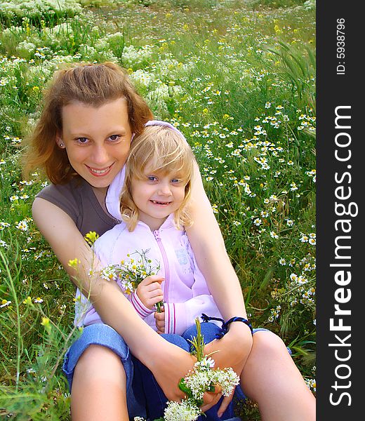 Young adult woman and child with the bouquets on a glade. Young adult woman and child with the bouquets on a glade.