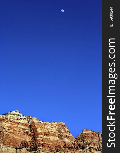 Red desert mountain peaks with blue sky and moon. Red desert mountain peaks with blue sky and moon