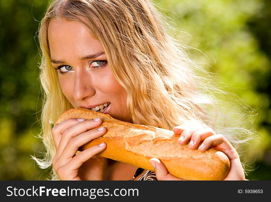 Smiling blond young woman biting white bread