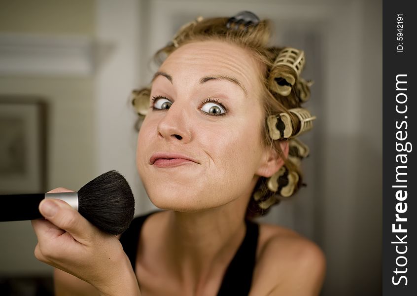 Woman in Curlers Applying Makeup with a Brush. Woman in Curlers Applying Makeup with a Brush