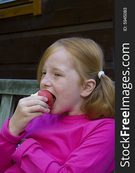 Little girl is eating an apple