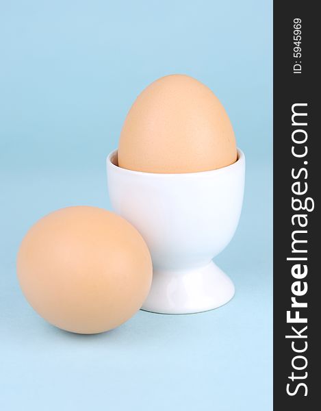 Hard boiled eggs in egg cups isolated against a blue background