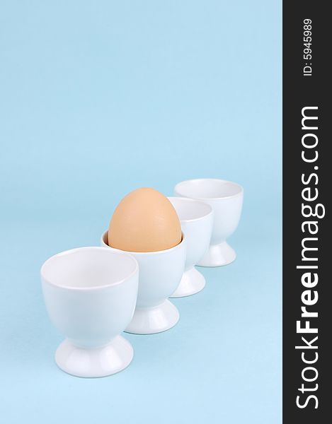 Hard boiled eggs in egg cups isolated against a blue background