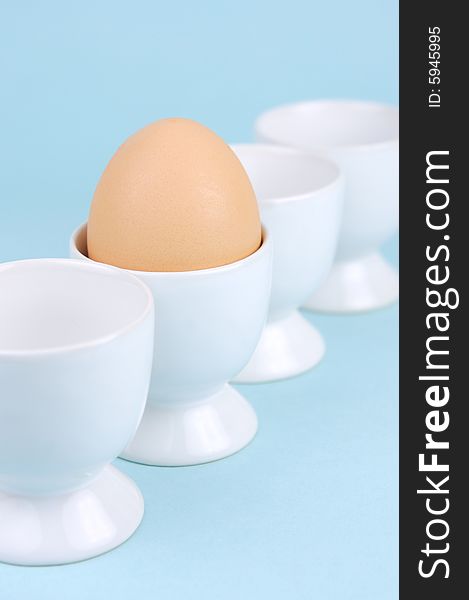 Hard boiled eggs in egg cups isolated against a blue background