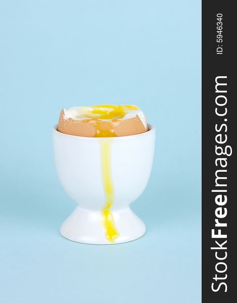 Hard boiled eggs in egg cups isolated against a blue background