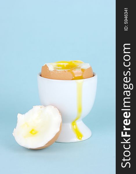 Hard boiled eggs in egg cups isolated against a blue background