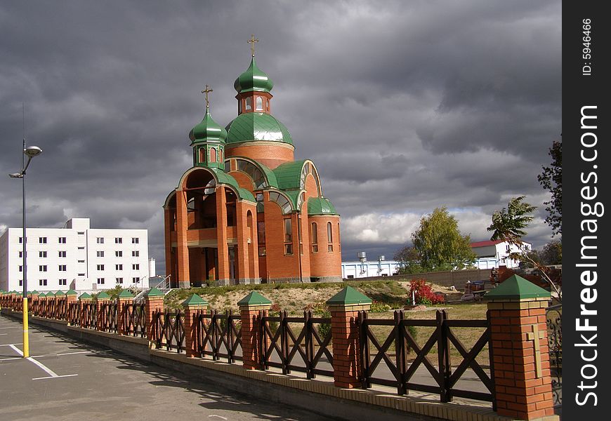 Orthodox church in the city of Brovary, Ukraine. The sky in dark clouds and only above church shines the sun.