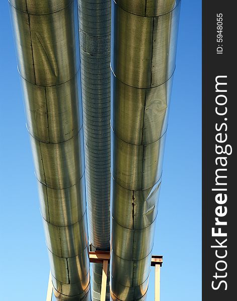 Industrial pipelines on pipe-bridge and electric power lines against blue sky. Industrial pipelines on pipe-bridge and electric power lines against blue sky