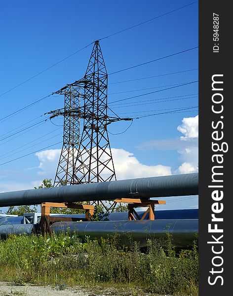 Industrial pipelines on pipe-bridge and electric power lines  against blue sky. Industrial pipelines on pipe-bridge and electric power lines  against blue sky