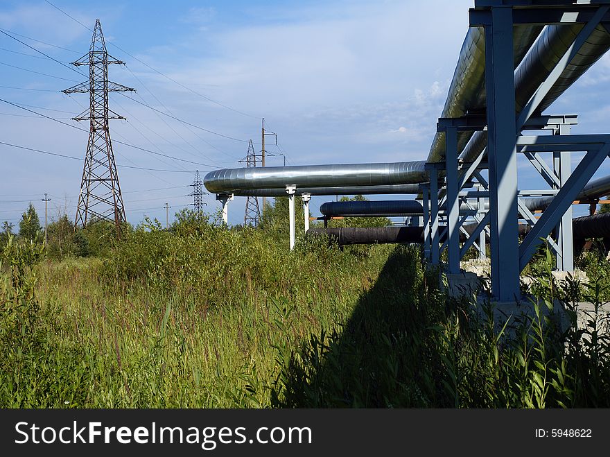 Industrial pipelines on pipe-bridge and electric power lines  against blue sky. Industrial pipelines on pipe-bridge and electric power lines  against blue sky