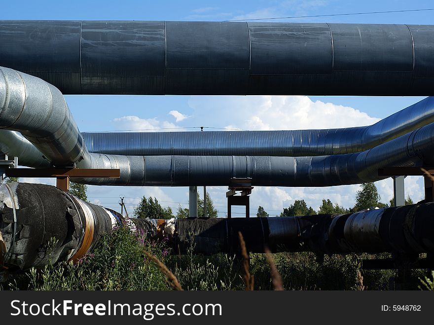 Industrial pipelines on pipe-bridge and electric power lines  against blue sky. Industrial pipelines on pipe-bridge and electric power lines  against blue sky