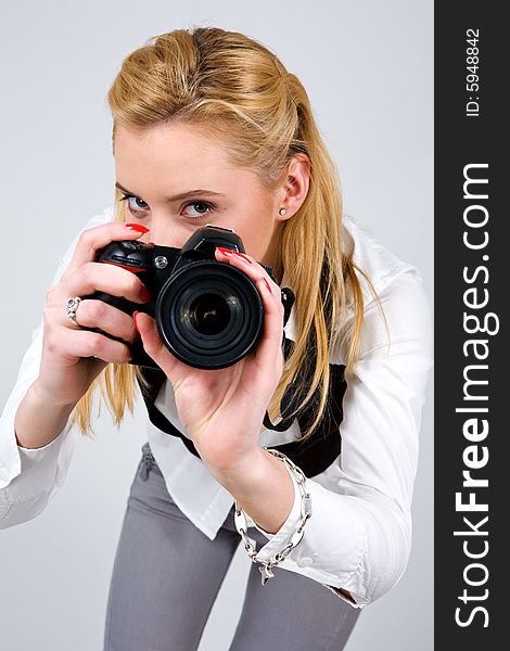 Young blond woman holding camera in studio. Young blond woman holding camera in studio
