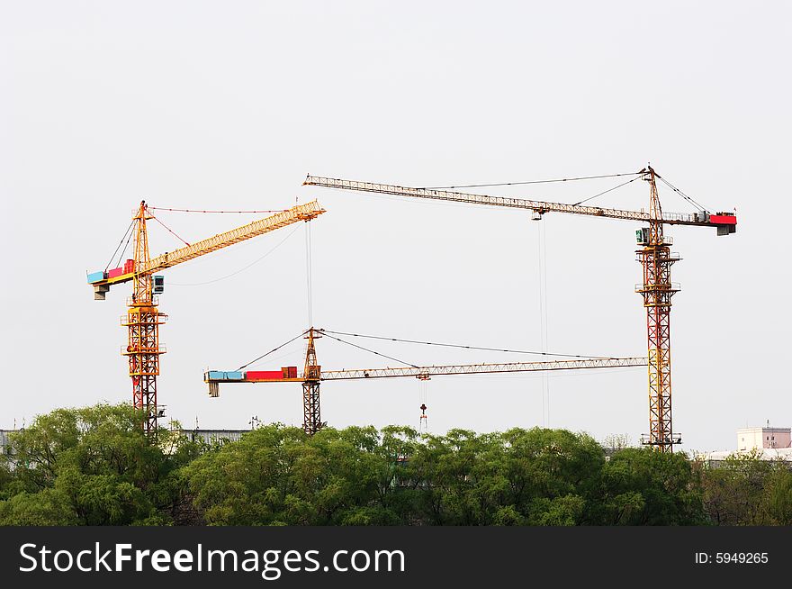 Three high cranes at building site.