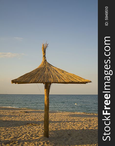 Wood and reed umbrella on picturesque tourist beach. Wood and reed umbrella on picturesque tourist beach