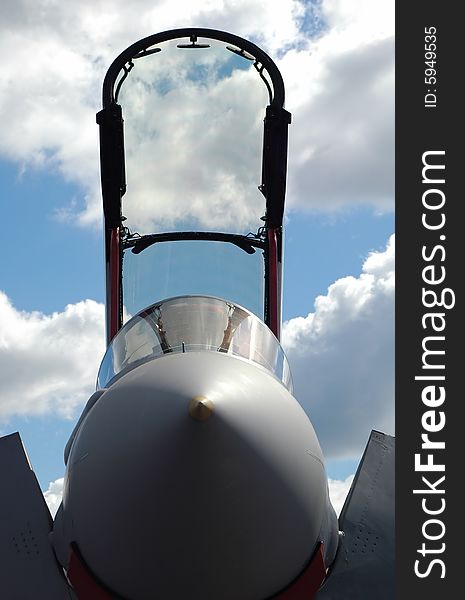 Jet fighter canopy silhouette against a blue cloudy sky