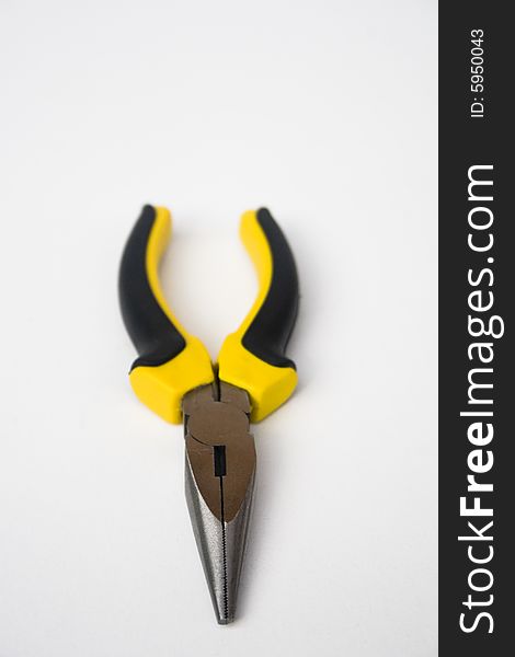 Yellow and black handled needle nose pliers against a white background