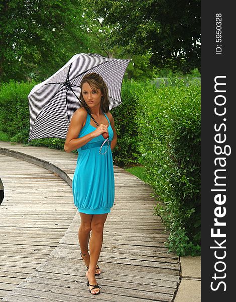 A picture of a woman fashioning a blue dress and umbrella. A picture of a woman fashioning a blue dress and umbrella