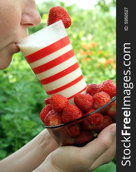 Red strawberry and glass milk in the hands