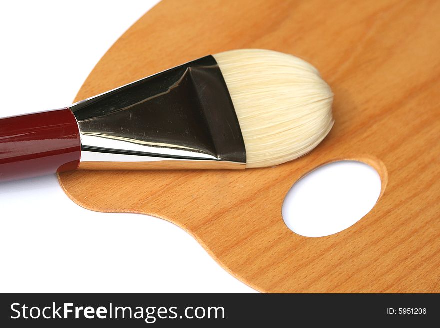 A new unused paintbrush in large size lies on a new palette on white background