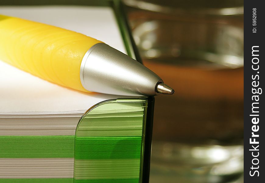 Yellow pen, stack of note pads and glass of water