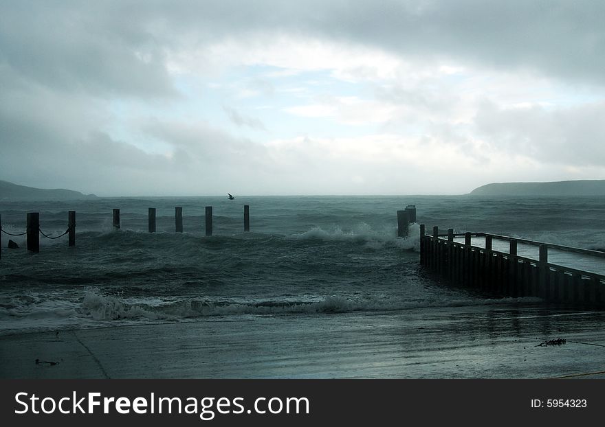 Stormy waves crashing on jetty with Mana Island in the background. Stormy waves crashing on jetty with Mana Island in the background