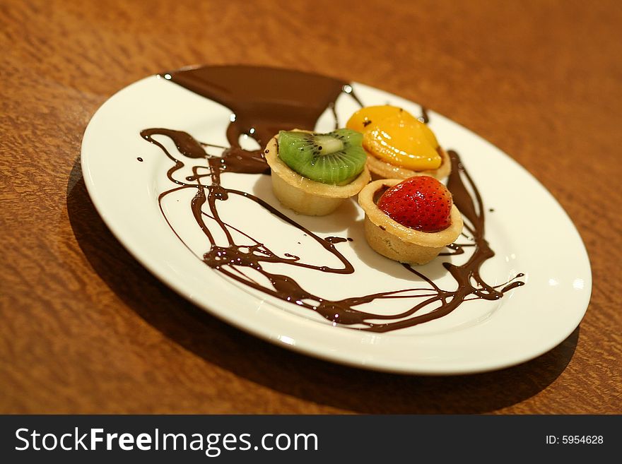 Fruit tarts with chocolate drizzled on plate