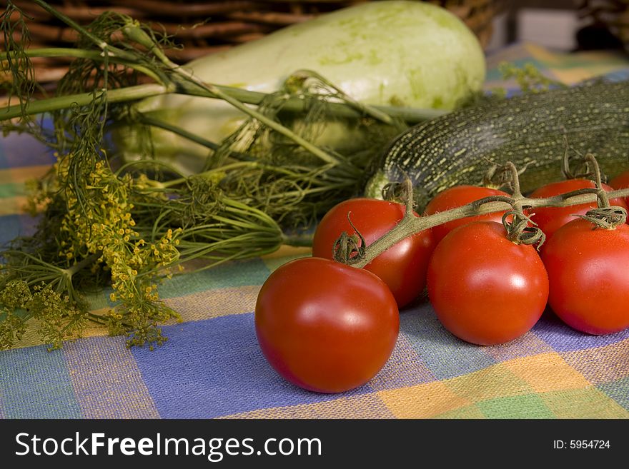 Cherry-tomatoes surrounded by other vegetables on the colorful tablecloth