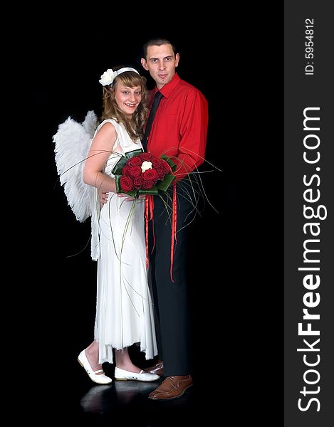 Young happy laughing wedding couple, bride with angel wings, on black background, studio shot. Young happy laughing wedding couple, bride with angel wings, on black background, studio shot