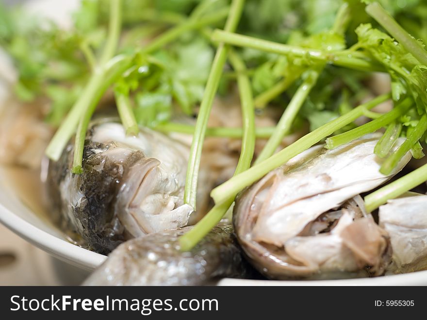 Steamed fish covered by fresh green caraway - traditional chinese dish. Steamed fish covered by fresh green caraway - traditional chinese dish