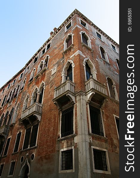 Corner of a historical venetian building with brick surface. View looking upwards, vertical perspective. Corner of a historical venetian building with brick surface. View looking upwards, vertical perspective.