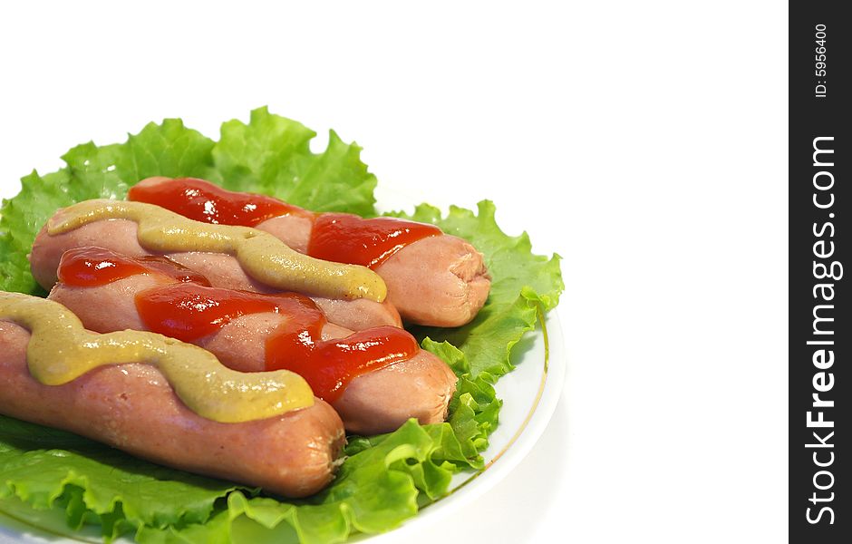 Sausages with ketchup and mustard on a white plate. Sausages with ketchup and mustard on a white plate