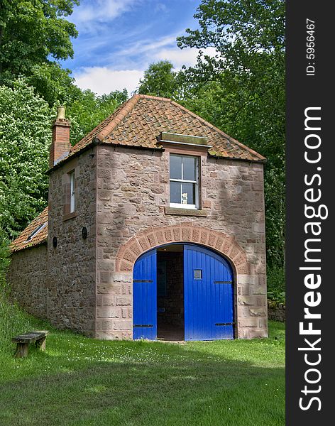 A boathouse with bright blue doors on the river Tweed on the Scottish English border. A boathouse with bright blue doors on the river Tweed on the Scottish English border