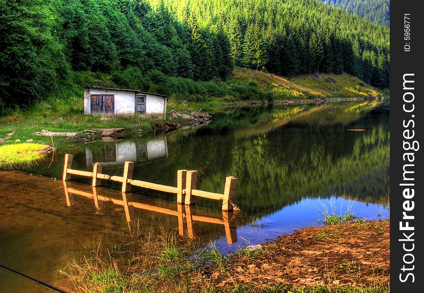 An abandoned house on the other side of a mountain lake. An abandoned house on the other side of a mountain lake