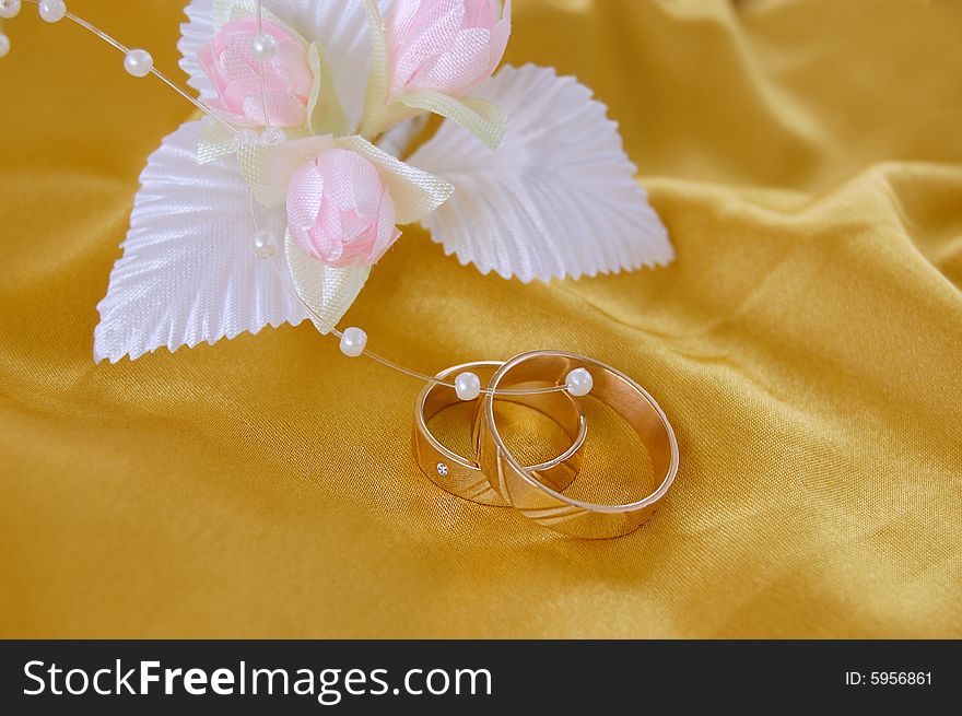 Wedding golden rings with decoration on golden satin