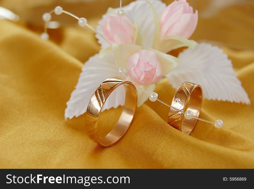 Wedding golden rings with decoration on golden satin