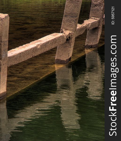 Part of an old submersed concrette bridge creating reflections on the water surface. Part of an old submersed concrette bridge creating reflections on the water surface