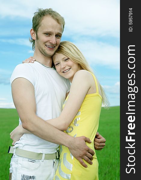 Man and woman in green field under blue sky