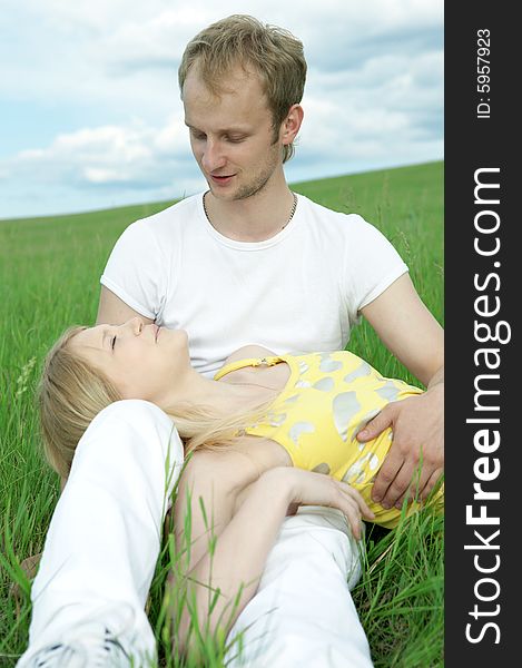 Man and woman in green field under blue sky