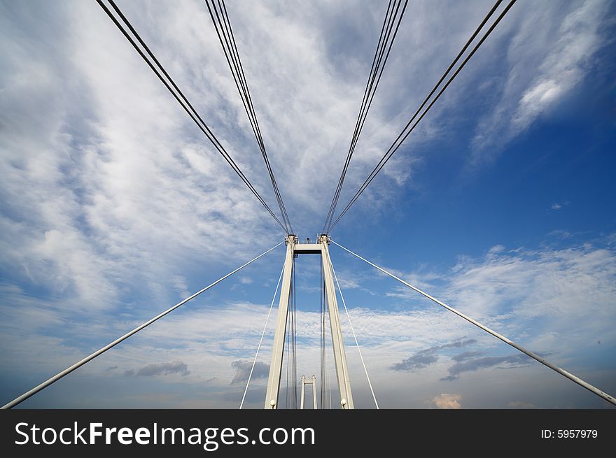 Cable of bridge over blue sky and clouds