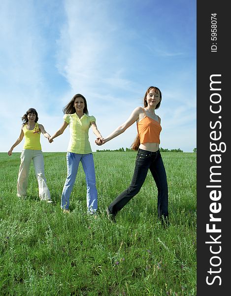 Three girlfriend in green field under blue sky