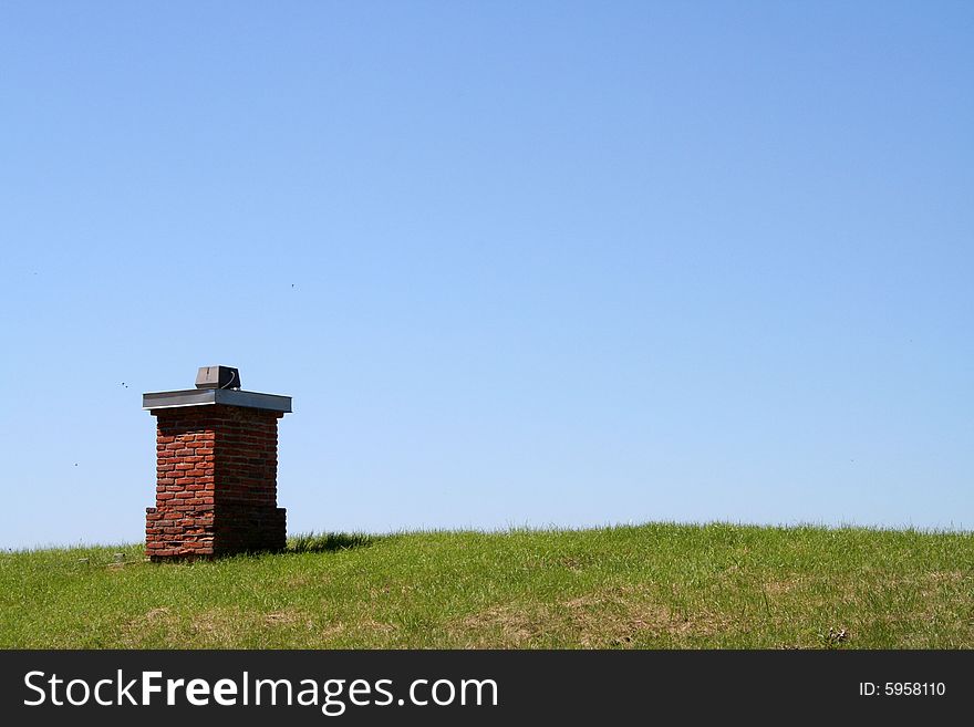 A chimney on a grass roof with a clear blue sky