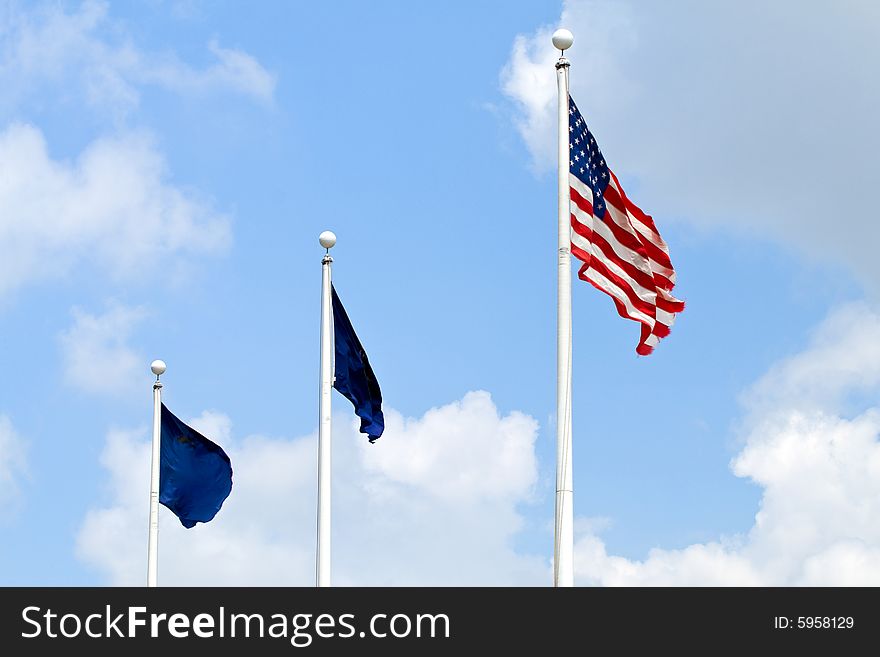 United States flag and two blue flags in a breeze against a scattered cloud sky. United States flag and two blue flags in a breeze against a scattered cloud sky