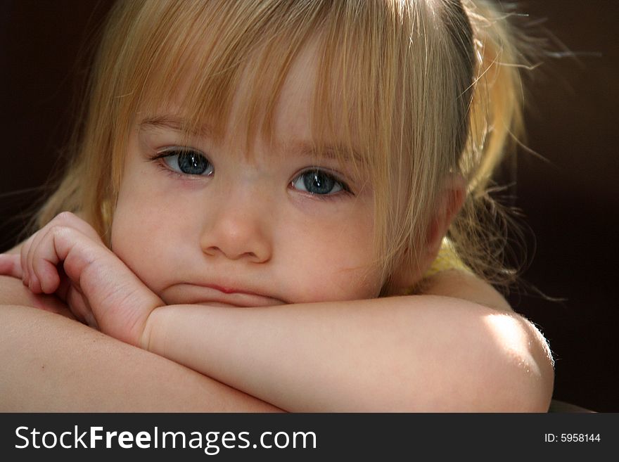 Little girl with pouty/pursed lips resting chin on crossed arms