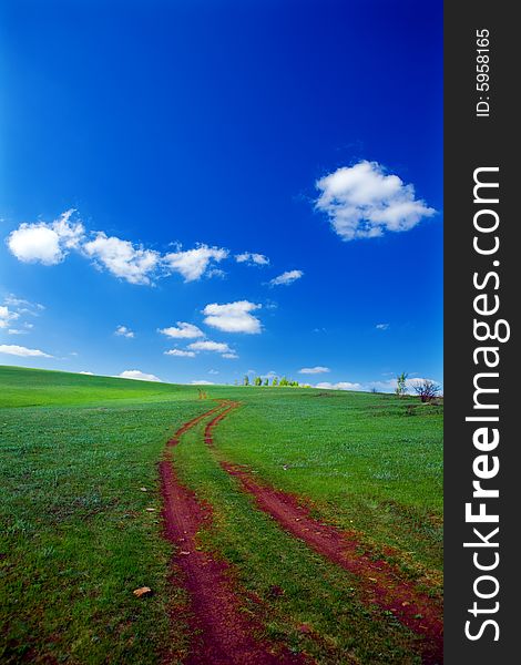 Nature background green field road and blue sky with clouds
