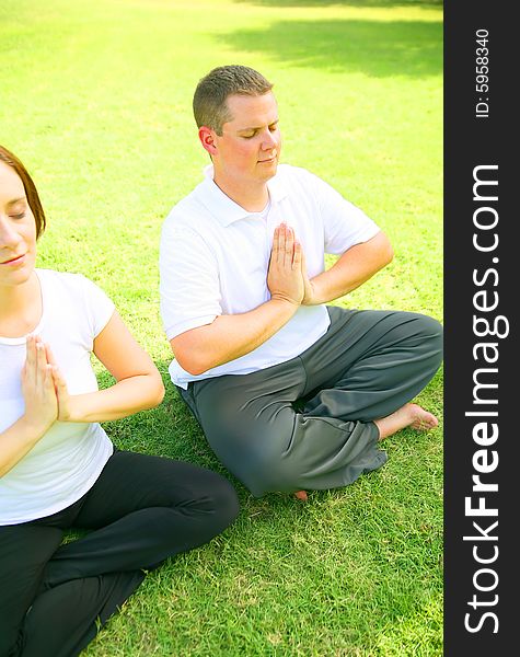 Young caucasian couple meditate outdoor in a park. concept for yoga, family activity or wellbeing. Young caucasian couple meditate outdoor in a park. concept for yoga, family activity or wellbeing