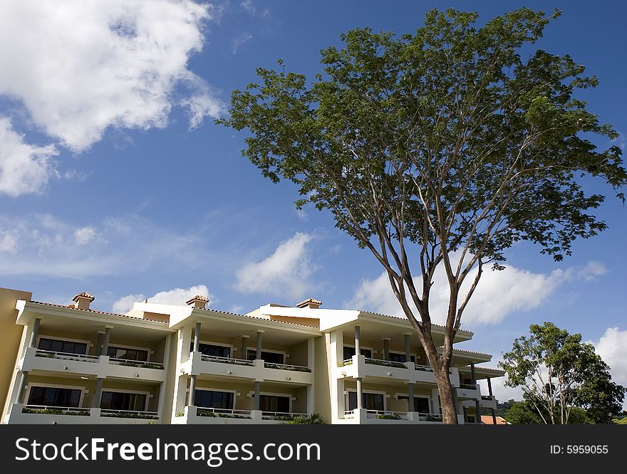 A resort building between tree and blue sky and clouds. A resort building between tree and blue sky and clouds