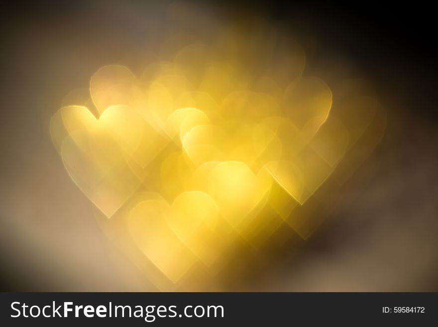 Festive background with defocused golden glitters, bokeh in a shape of a heart. Festive background with defocused golden glitters, bokeh in a shape of a heart.